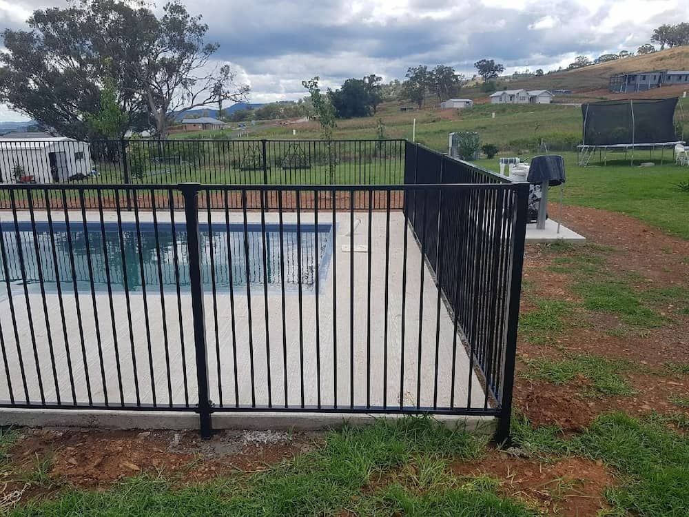 A Black Metal Fence Surrounds A Swimming Pool — Anne & Ron Johnson Fencing in Werris Creek, NSW