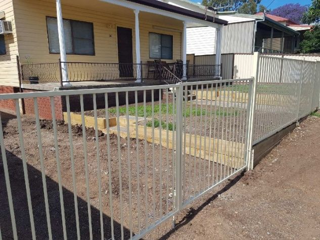 A Fence With A Gate Stands In Front Of A House — Anne & Ron Johnson Fencing in Werris Creek, NSW