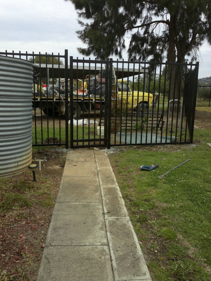 A Man Wearing A Yellow Shirt And Hat Is Busy Fixing A Fence — Anne & Ron Johnson Fencing in Werris Creek, NSW