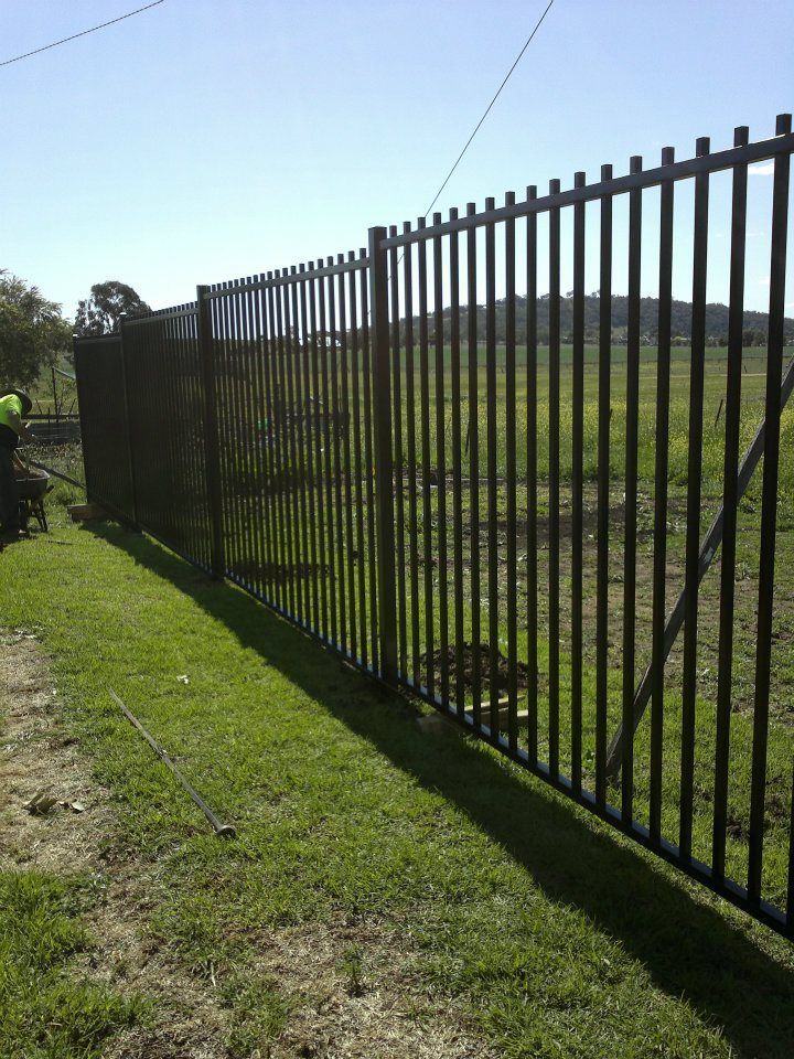 A Man Is Repairing A Fence In A Yard — Anne & Ron Johnson Fencing in Werris Creek, NSW