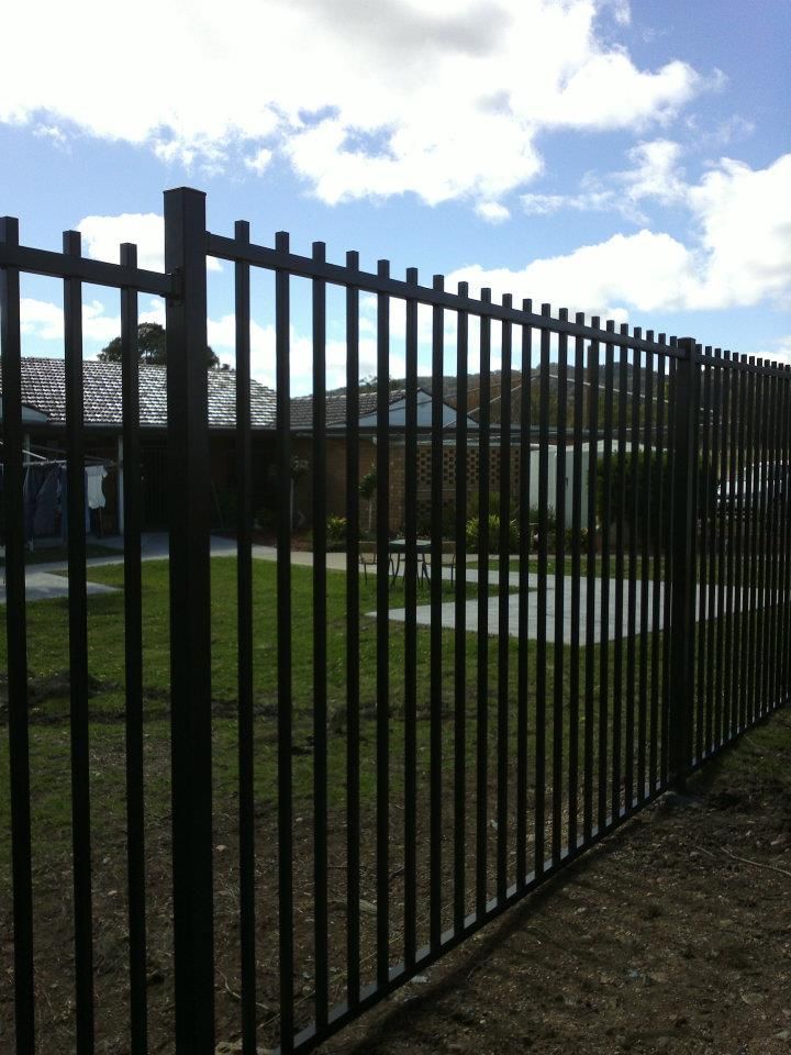 A Black Fence Stands In Front Of A House — Anne & Ron Johnson Fencing in Werris Creek, NSW