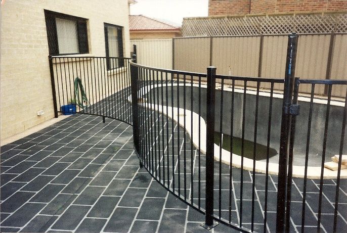 A Black Fence Surrounds A Backyard Pool — Anne & Ron Johnson Fencing in Werris Creek, NSW