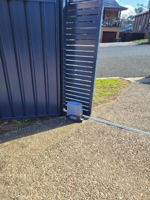 An Automatic Gate With A Small White Box Placed On The Ground Nearby — Anne & Ron Johnson Fencing in Werris Creek, NSW