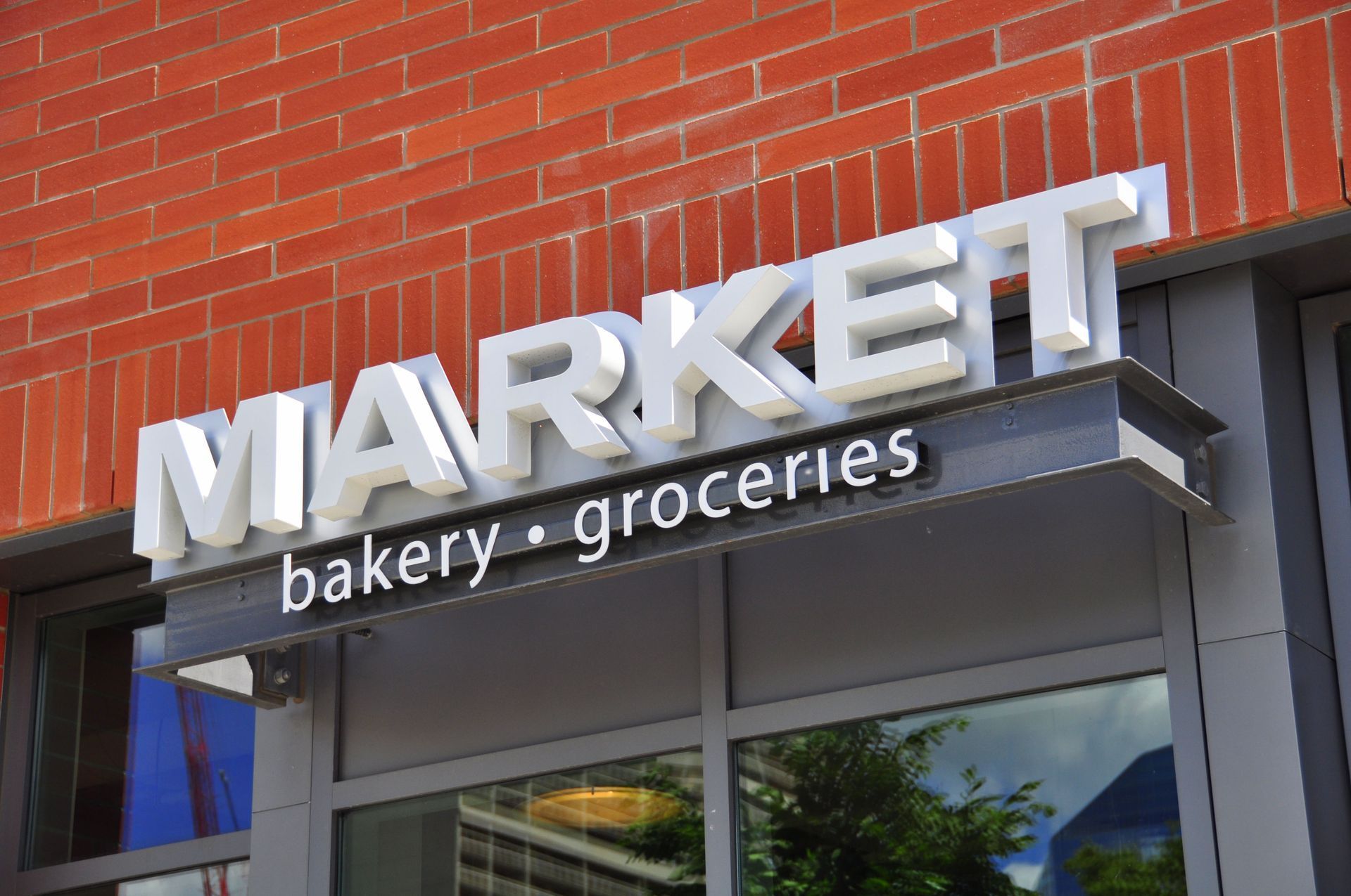 Storefront sign reading “MARKET” with “bakery • groceries” on a red brick building.