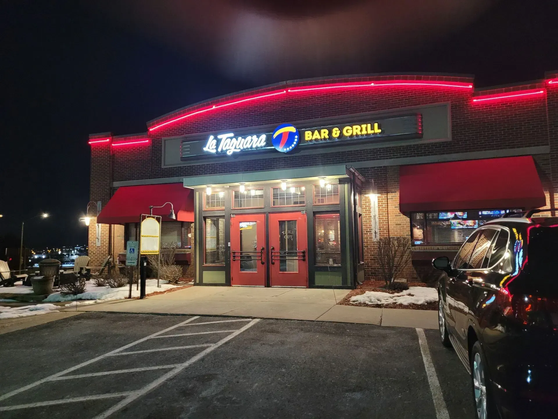 Tropicana Bar & Grill storefront at night with red neon trim and parked cars