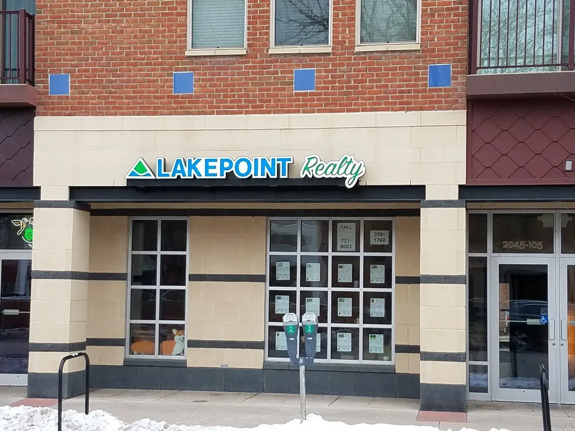 LakePoint Realty storefront with brick facade, glass doors, and hanging property listings