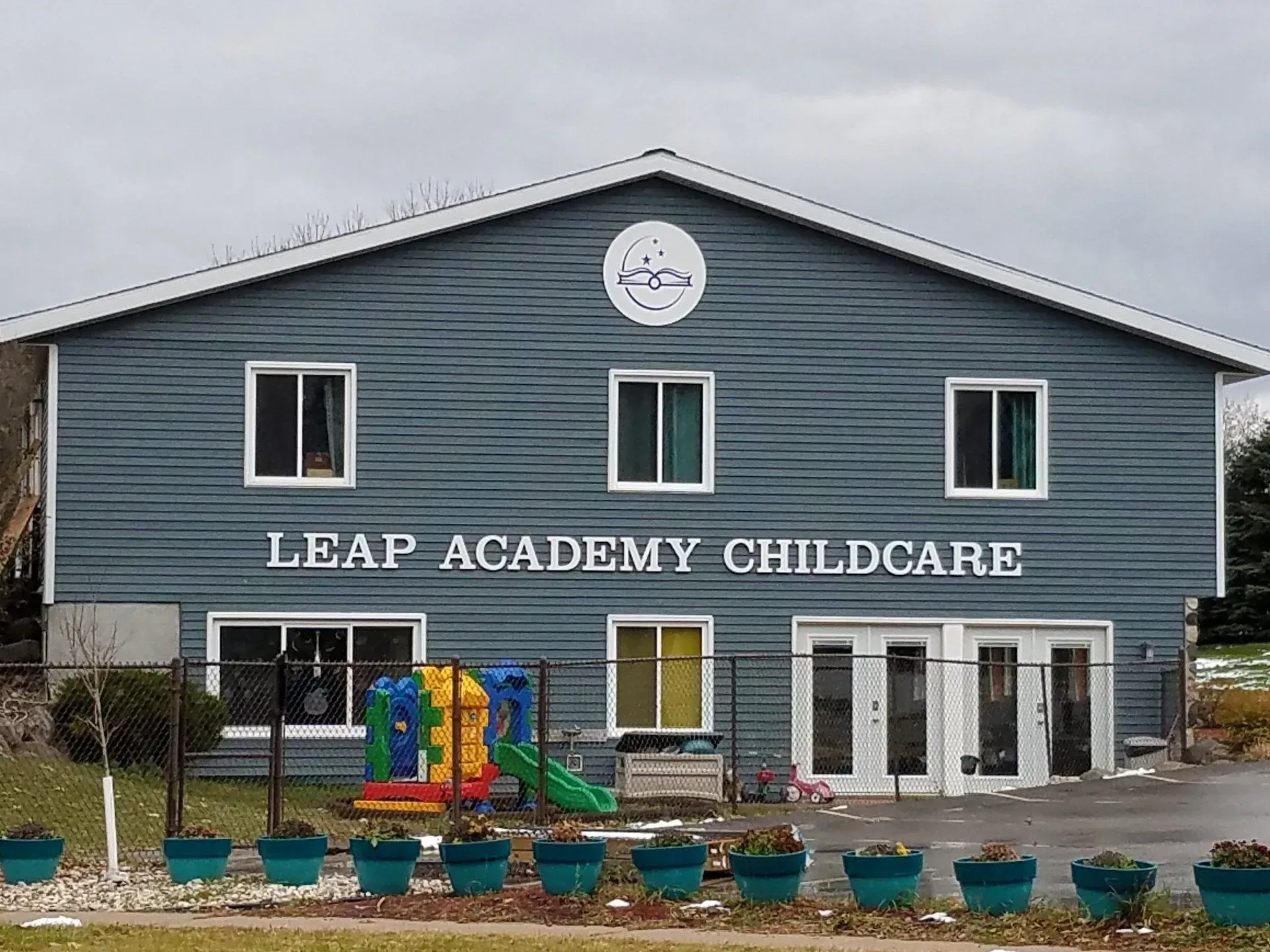 LEAP Academy Childcare building with blue siding, white lettering, and a colorful playground in front
