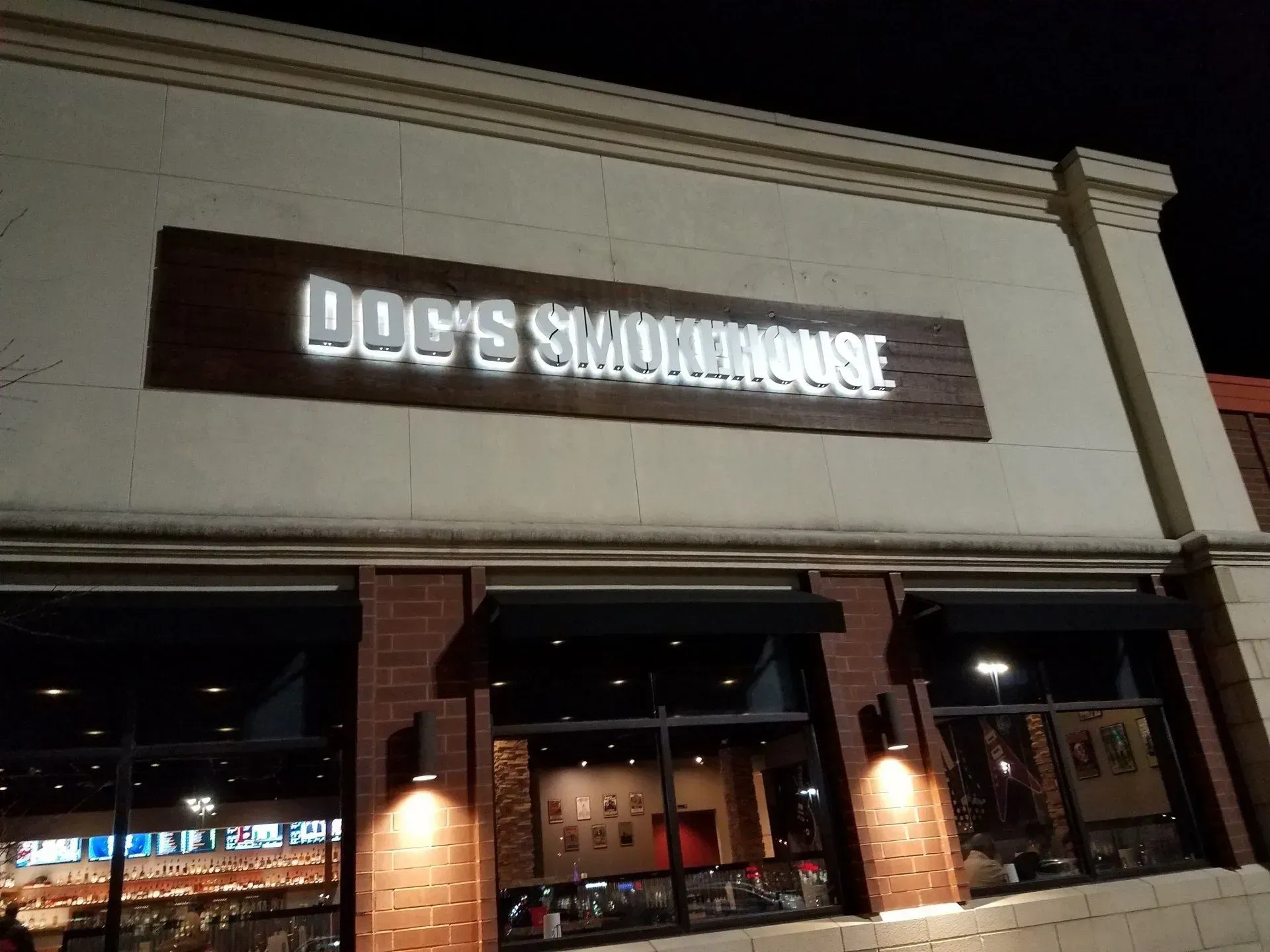Exterior of Joe’s Smokehouse restaurant at night, with a lit sign above the brick storefront.