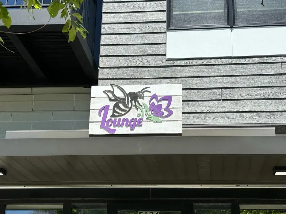 Purple and white “Lounge 53” sign on a gray building exterior