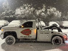 A tow truck is parked in the snow in a parking lot.