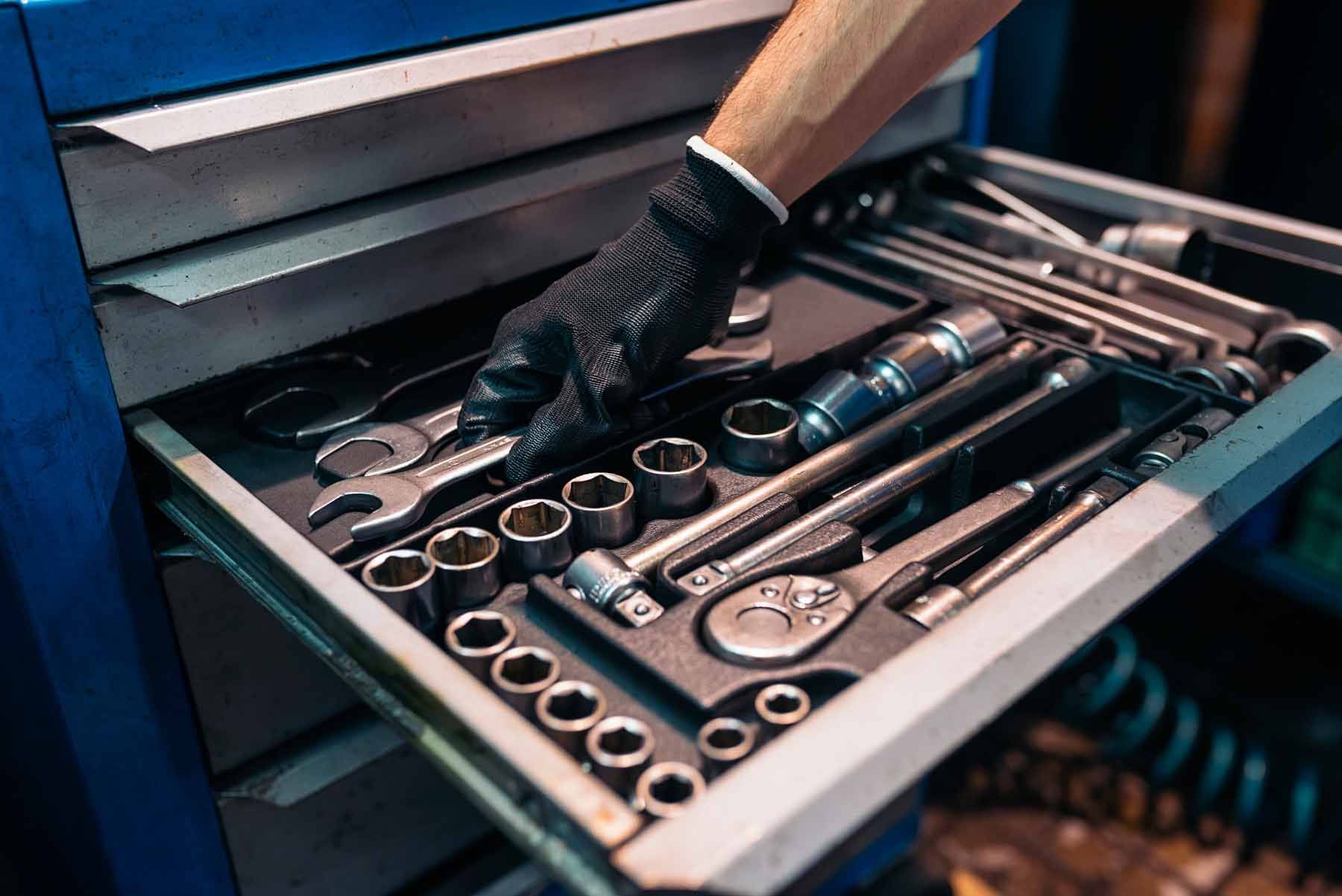 A person is reaching into a drawer filled with tools.