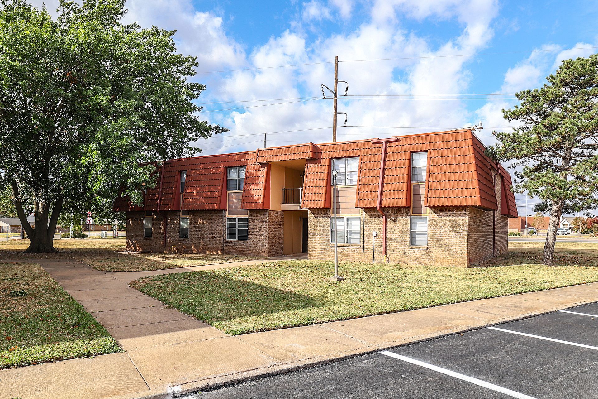 Two-story brick apartment building with red tiled roof and windows.