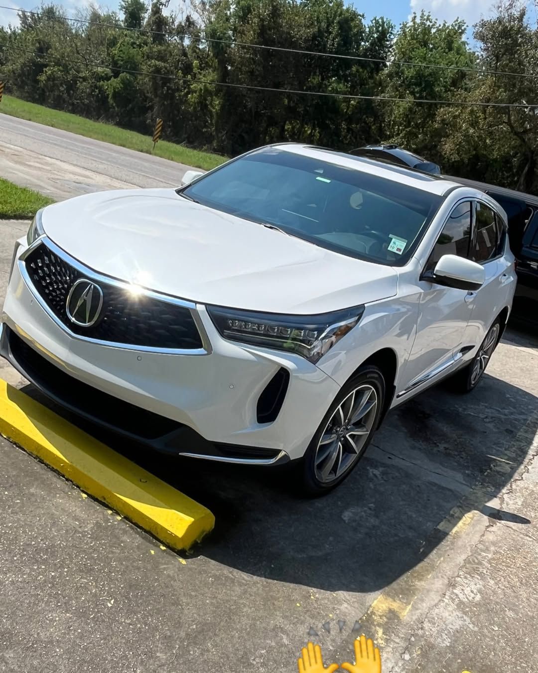 A white car is parked on a yellow curb in a parking lot.