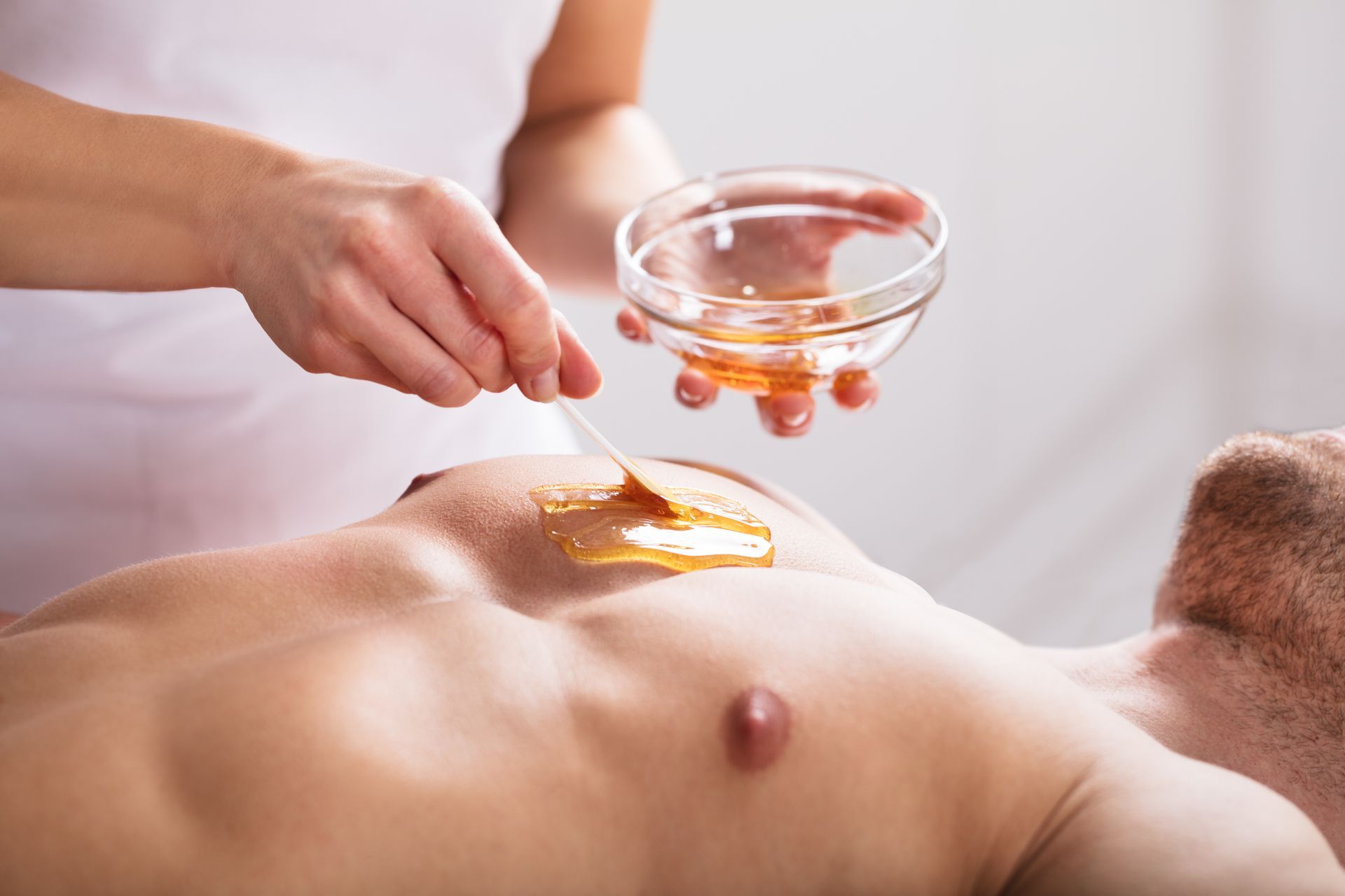 Ein Mann bekommt eine Wachsbehandlung auf der Brust.