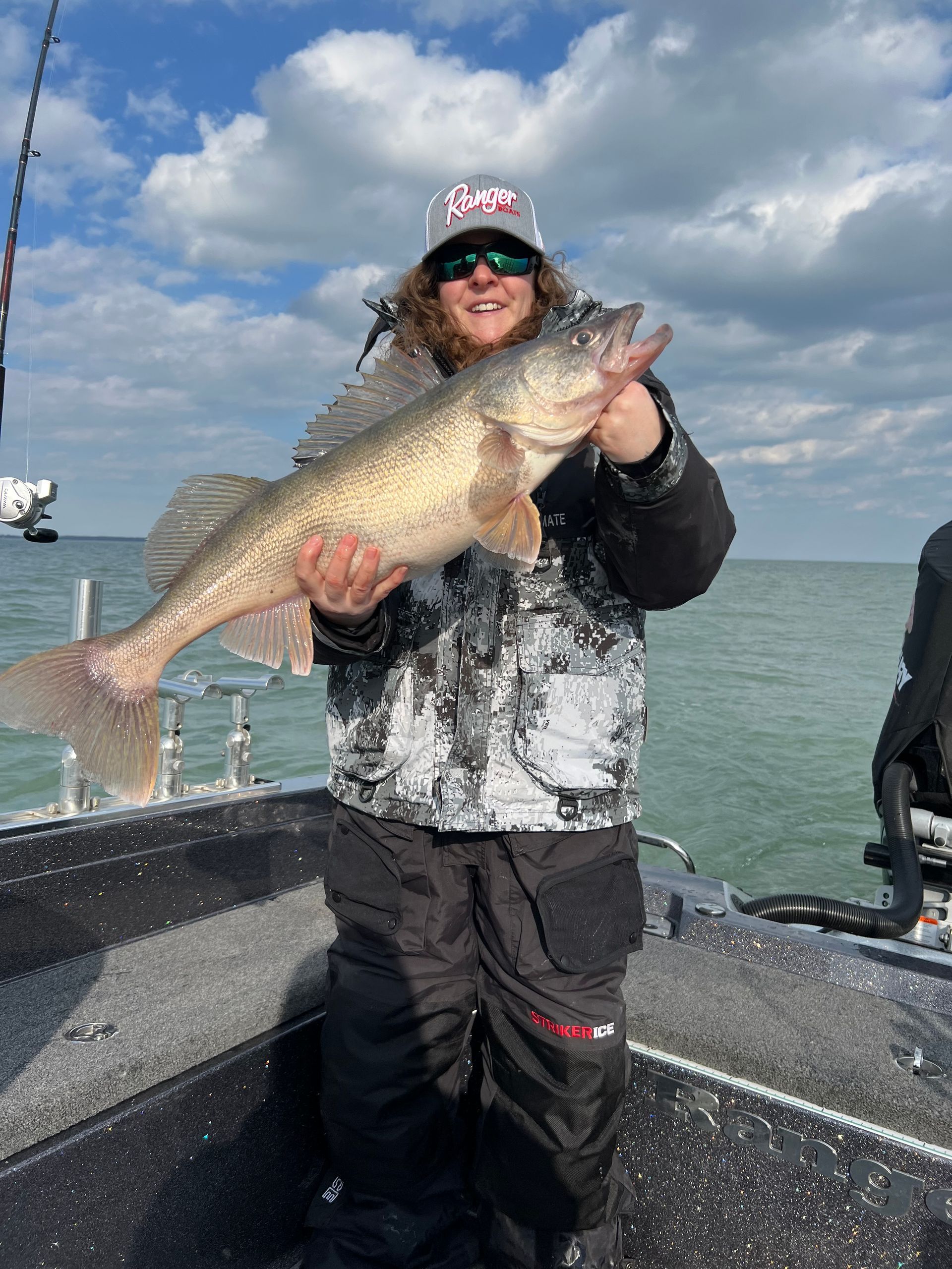 A man is holding a large fish on a boat.