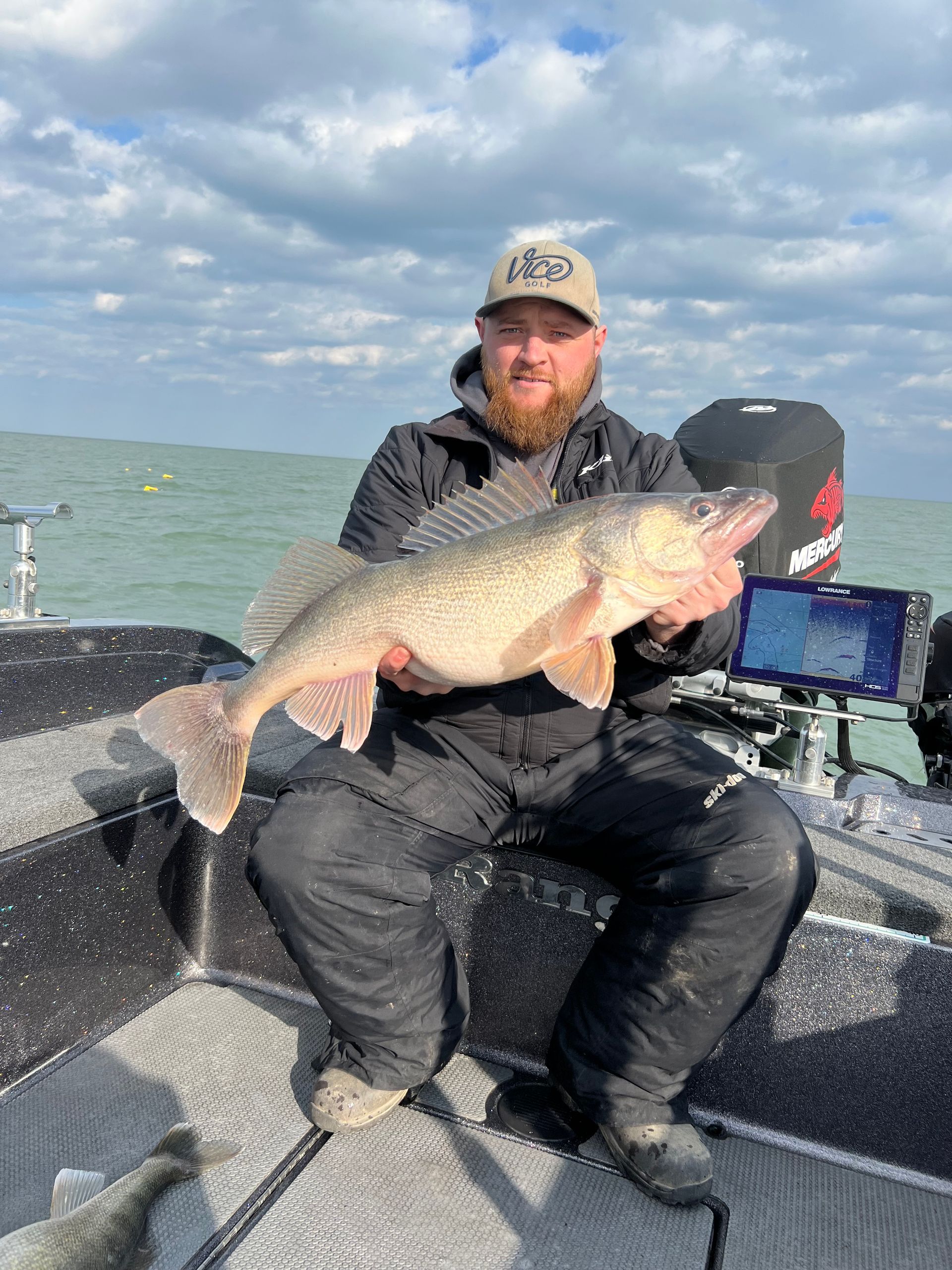 A man is sitting on a boat holding a large fish.