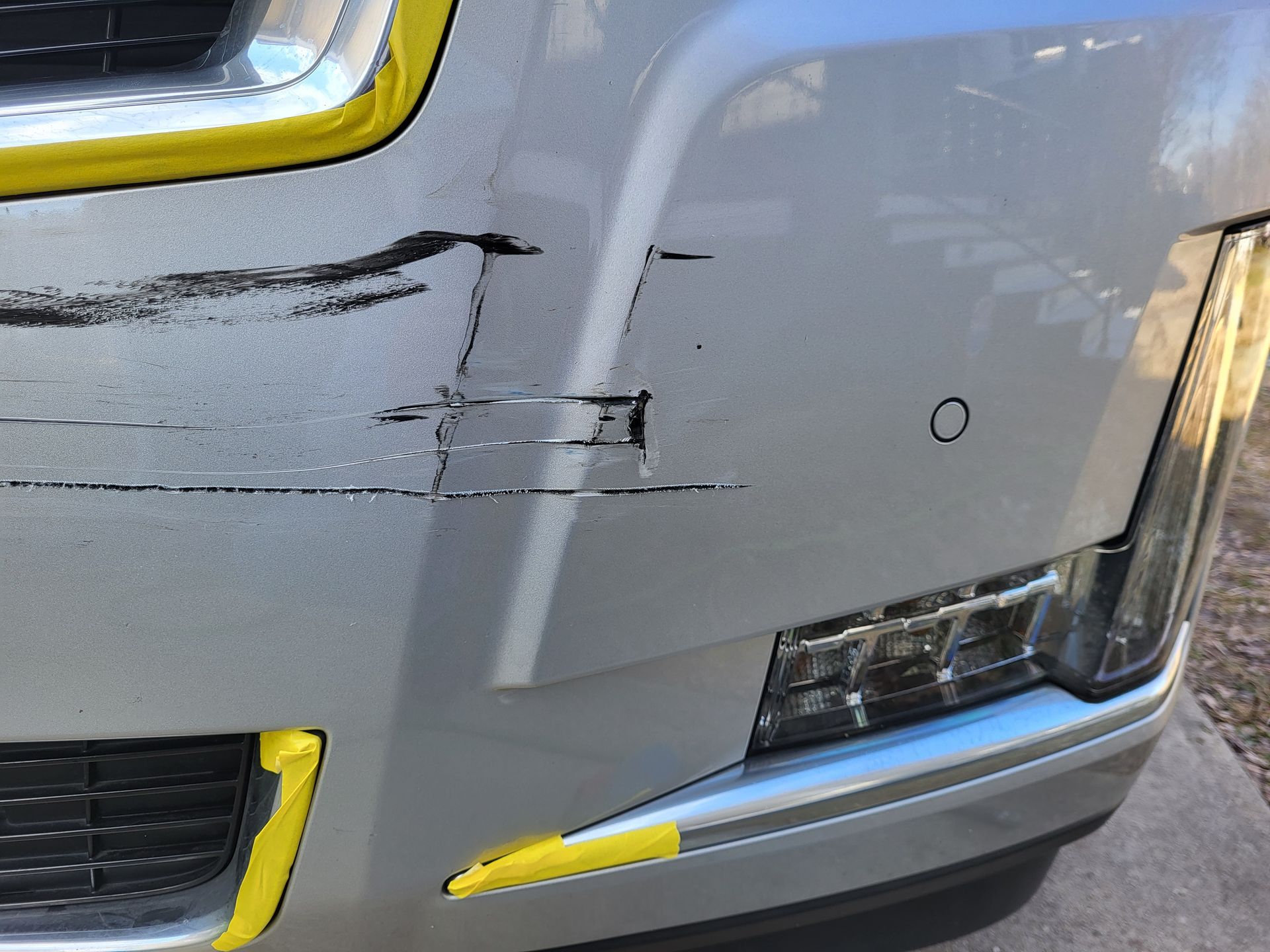 A close up of a car with a scratch on the front bumper.