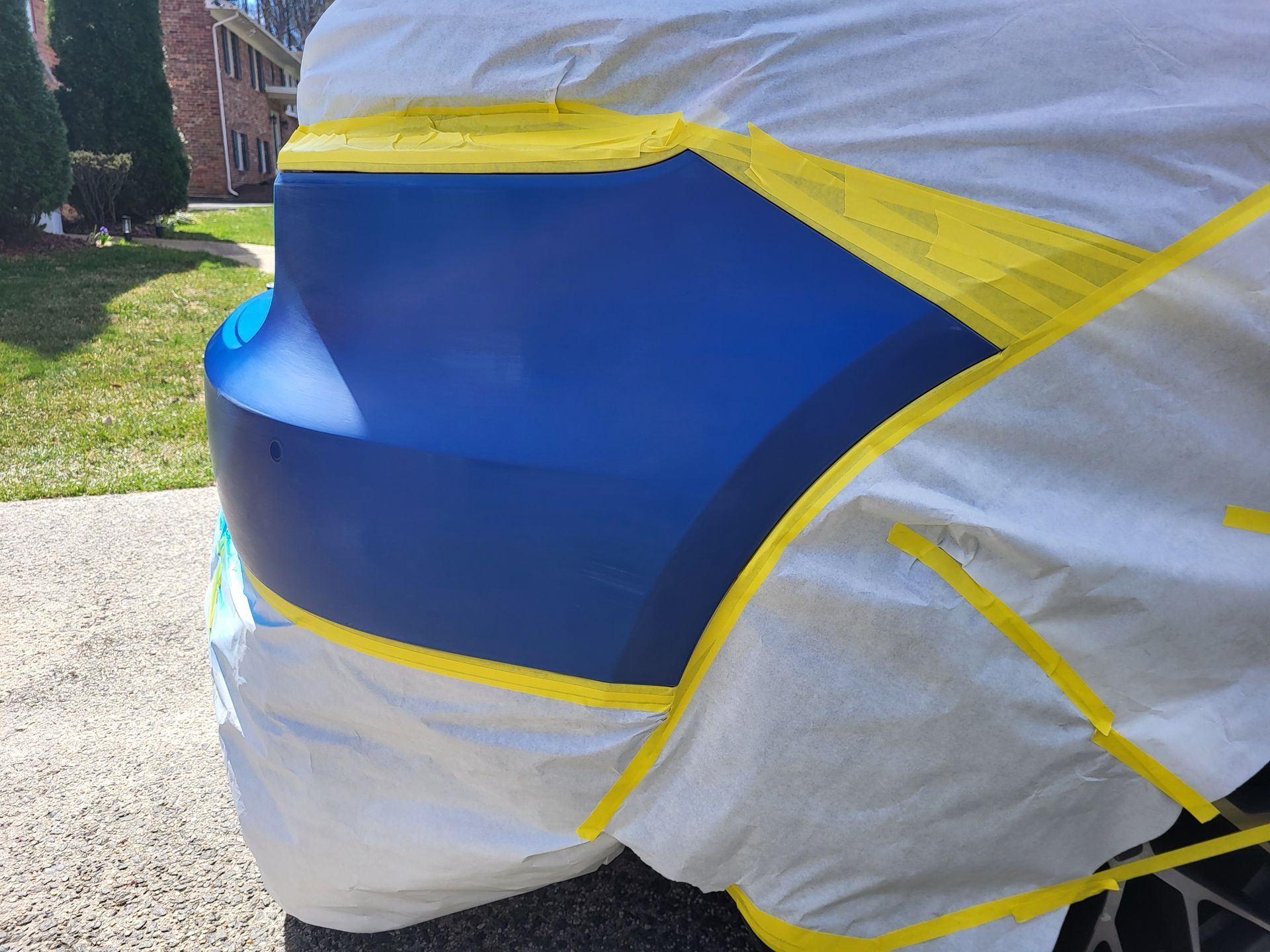 A blue car is being painted with yellow tape.