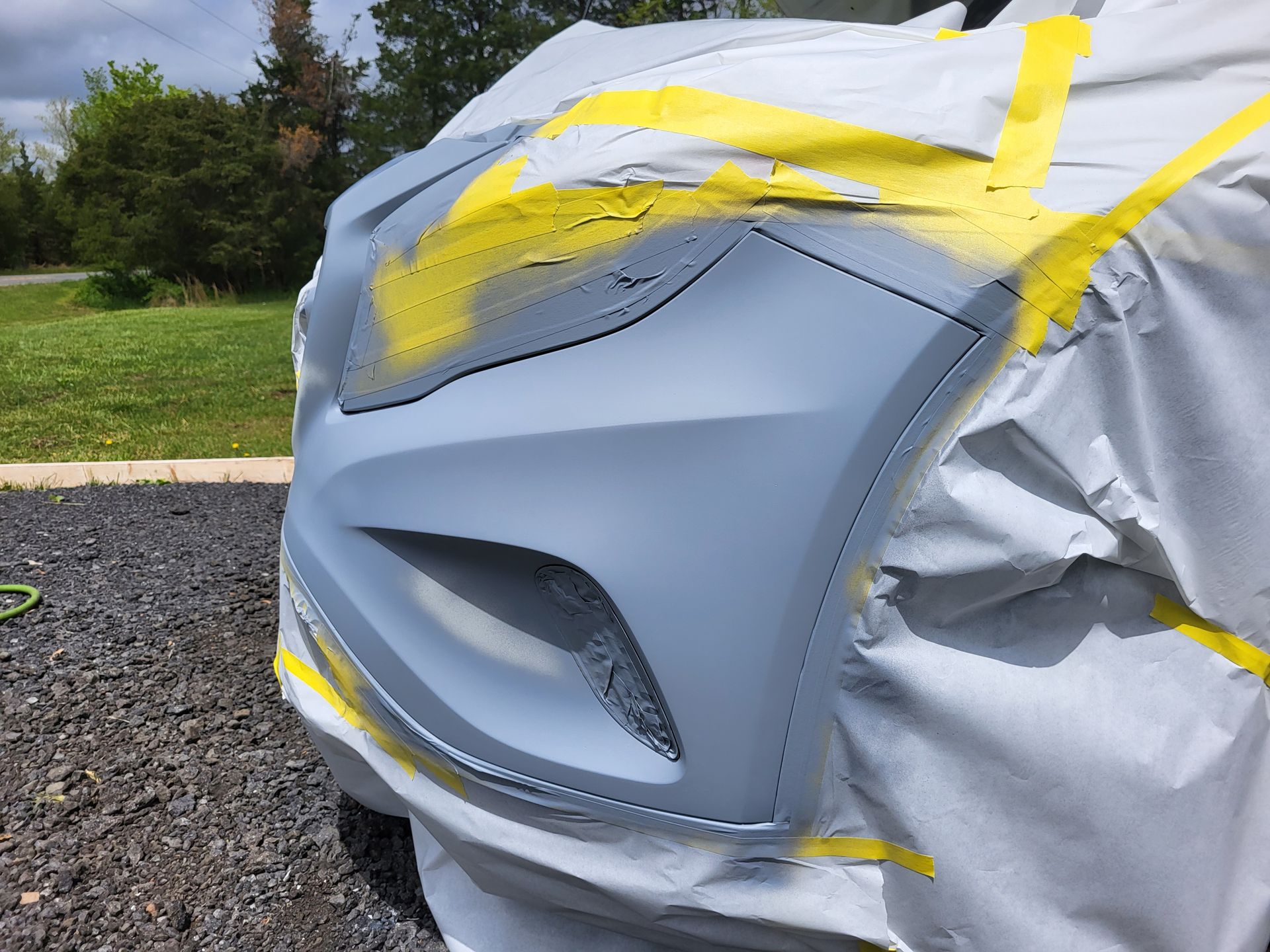The front bumper of a car is being painted.