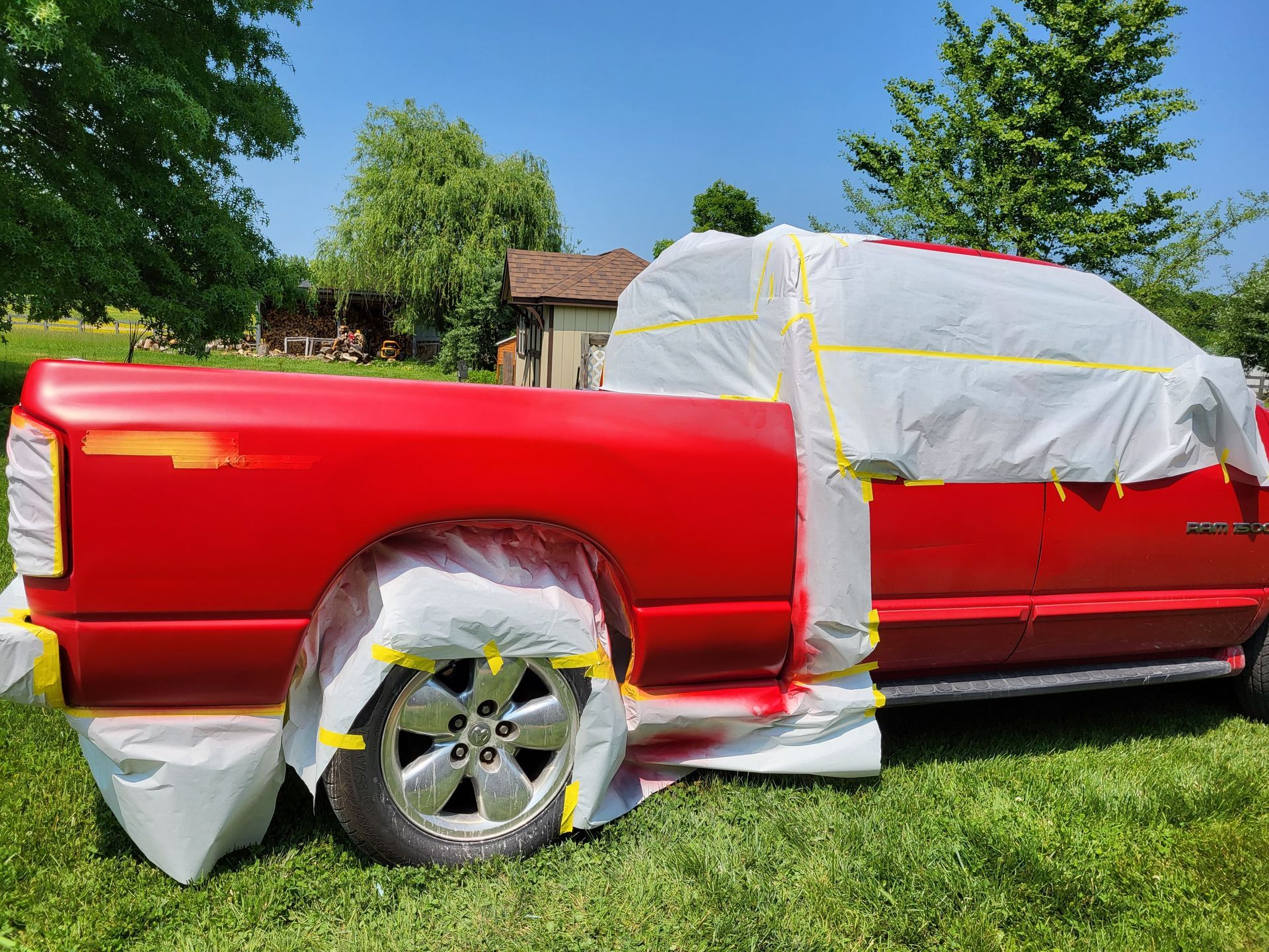 A red truck is being painted in a grassy field.