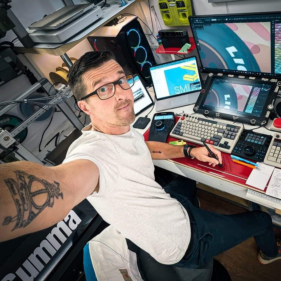 A man with a tattoo on his arm is sitting at a desk