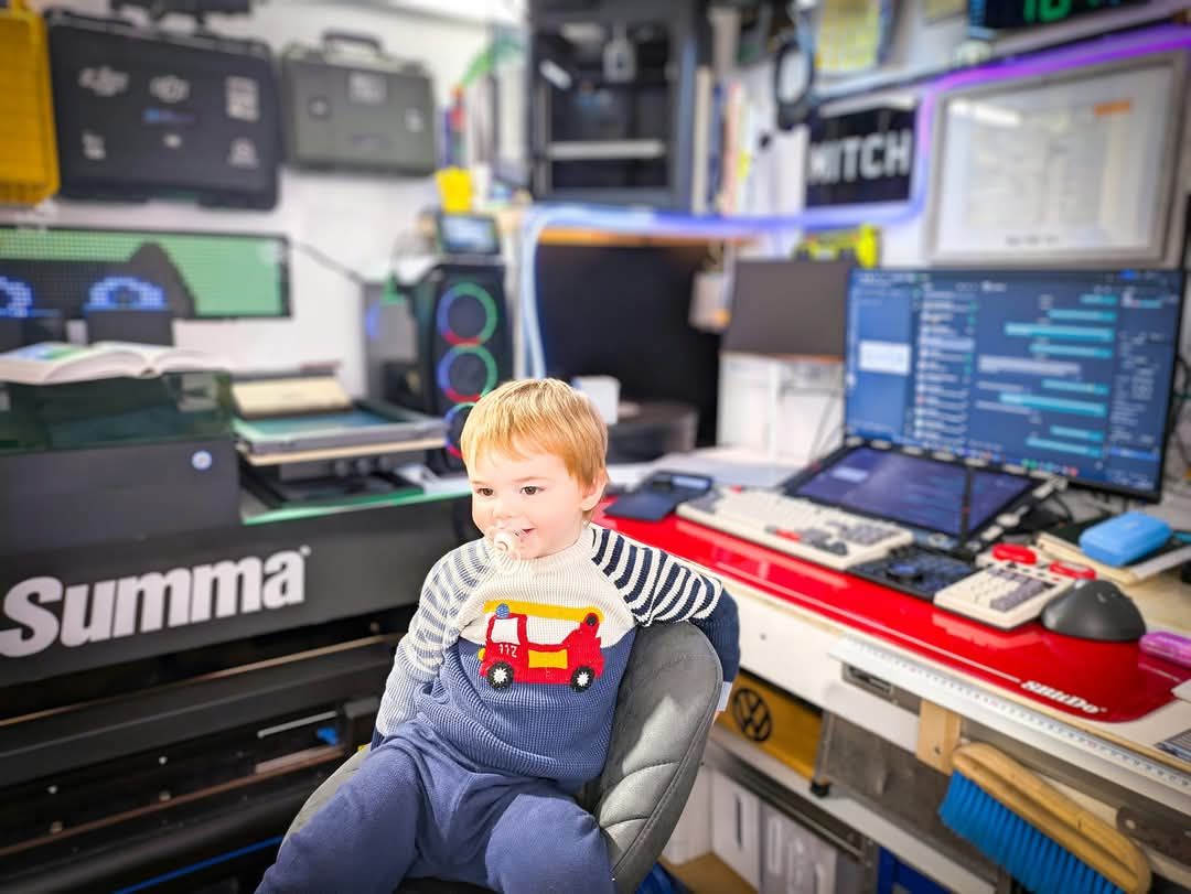 A little boy is sitting in a chair in front of a computer.