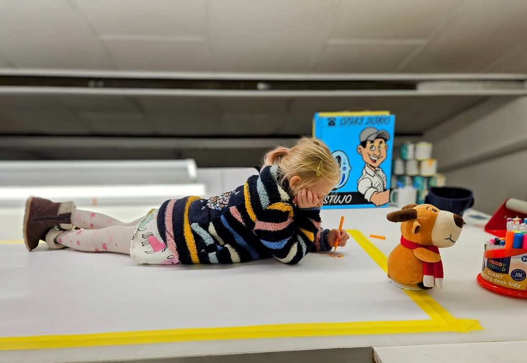 A little girl is laying on the floor playing with toys.
