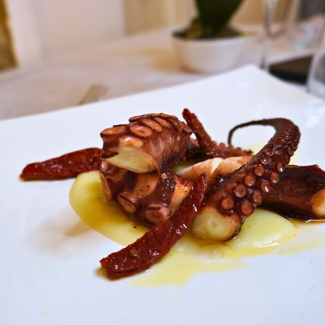 Un tavolo e delle sedie in un ristorante con un vaso di fiori sopra.