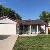 A house with a large driveway and a large lawn in front of it.