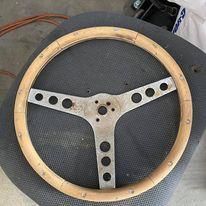 A wooden steering wheel is sitting on top of a chair.