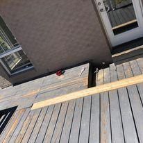 A wooden deck in front of a house with a door.