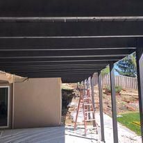 A black patio cover is being built on the side of a house.