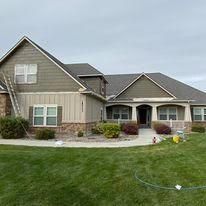 A large house with a ladder in front of it is being painted.