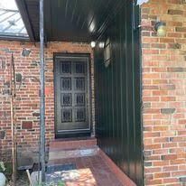 A brick house with a black door and a porch.