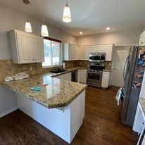 A kitchen with granite counter tops , stainless steel appliances , and hardwood floors.