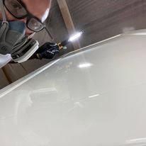 A man wearing a mask and glasses is working on a white car.