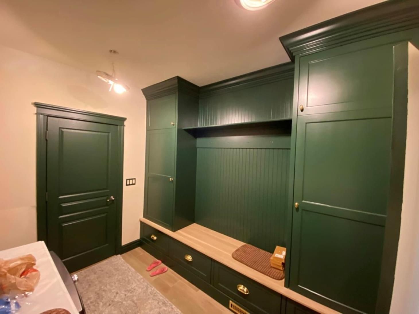 A room with green cabinets and a bench in it.