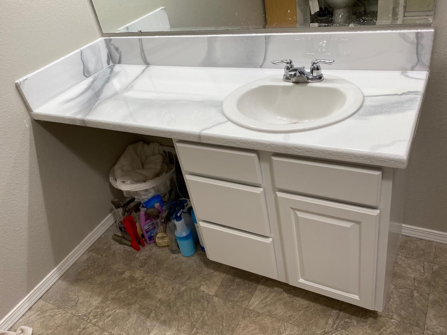 A bathroom with a sink , cabinets and a mirror.