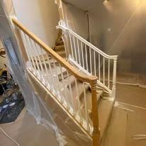 A staircase with a white railing is covered in plastic.
