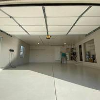 A large empty garage with a garage door open and a ceiling fan.