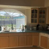 A kitchen with wooden cabinets , a sink , and a large window.