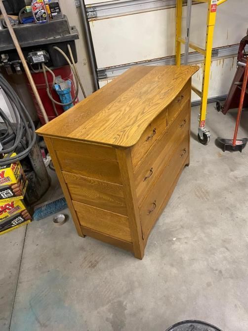 A wooden dresser is sitting on a concrete floor in a garage.