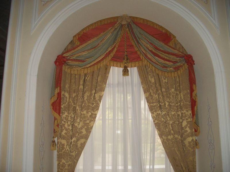 Tende decorate in una nicchia ad arco; tessuti color oro, rosso e verde acqua.