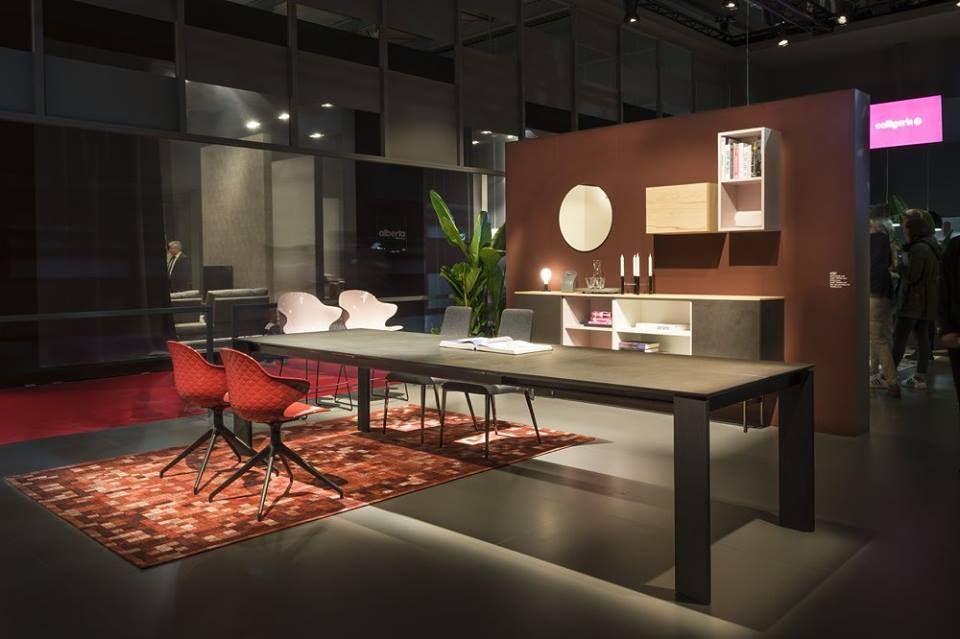 Moderno ufficio con tavolo lungo, sedie rosse, tappeto e parete color bordeaux.