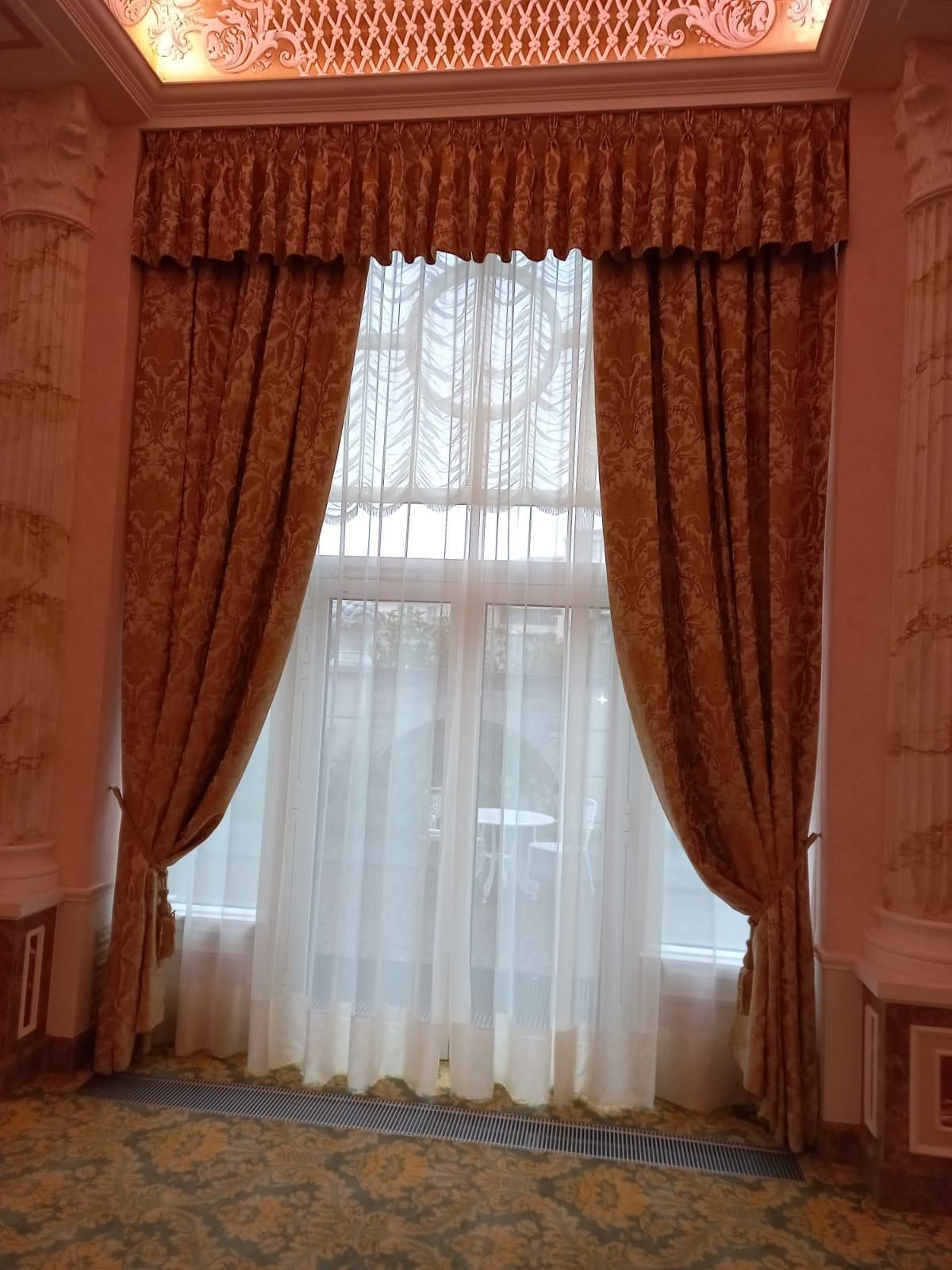 Finestra con tende con motivi dorati, tende bianche trasparenti e balza
