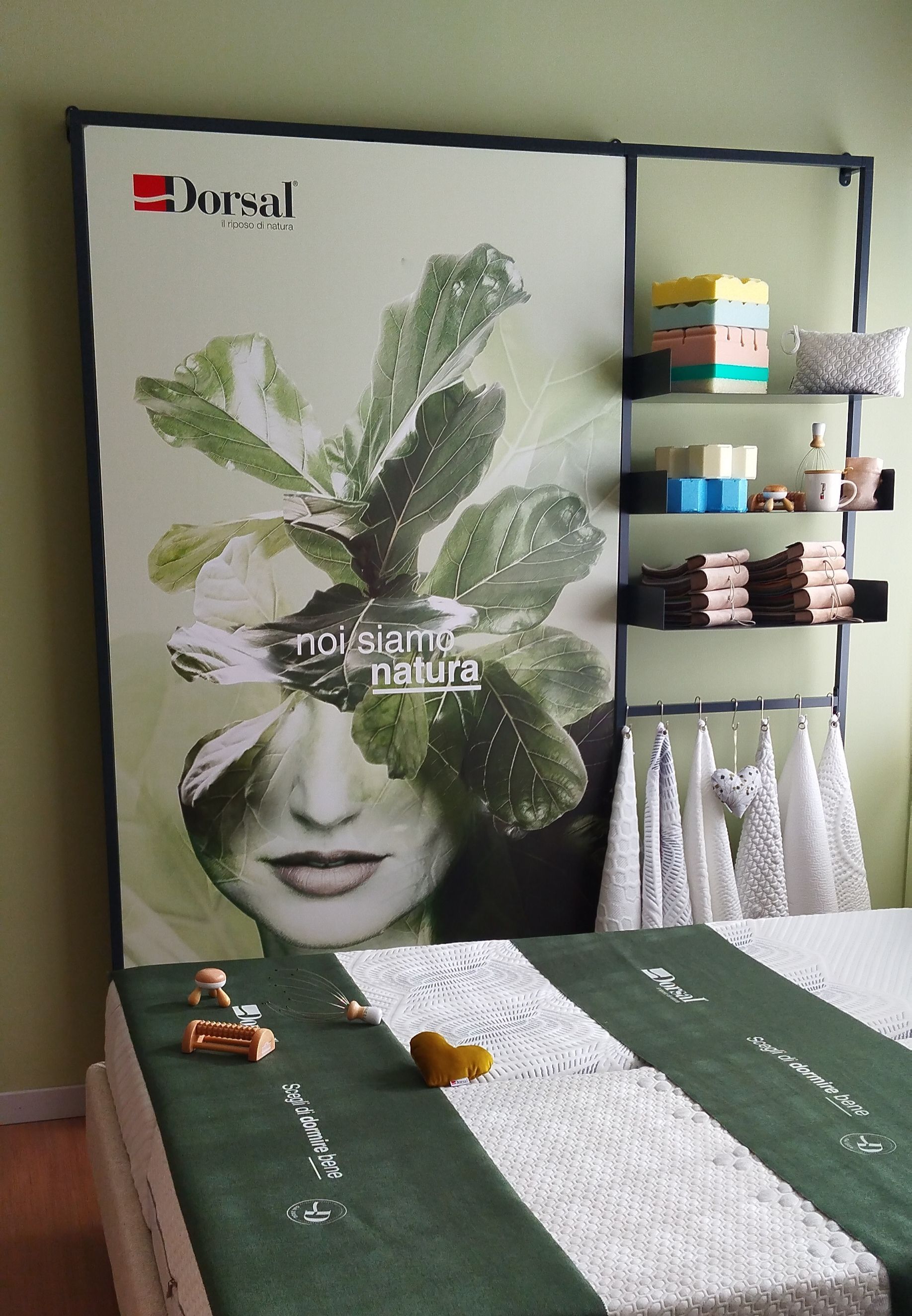 Letto verde e bianco con poster e mensole. Il poster raffigura un volto di donna velato da foglie. 