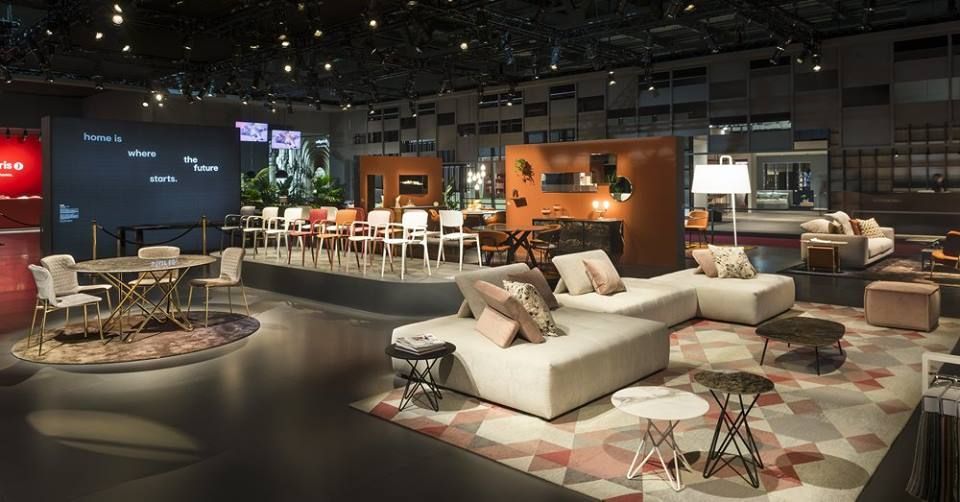 Mostra di design d'interni con sedute e tavoli su un ampio spazio aperto.