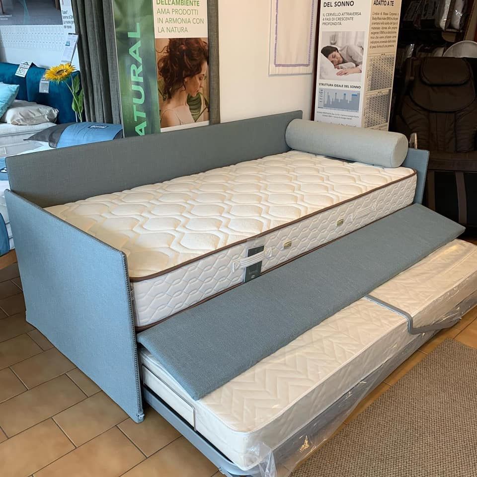 Divano letto blu con letto estraibile, due materassi e un cuscino a rullo.