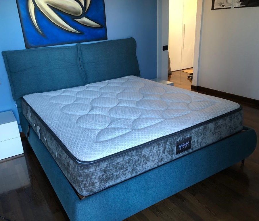 Letto imbottito blu con materasso bianco in una camera da letto.