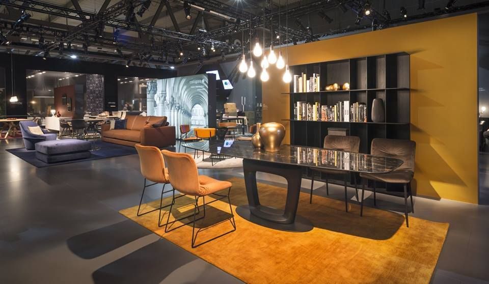 Showroom di mobili moderni: tappeto arancione, tavolo nero con sedie, scaffali, illuminazione.